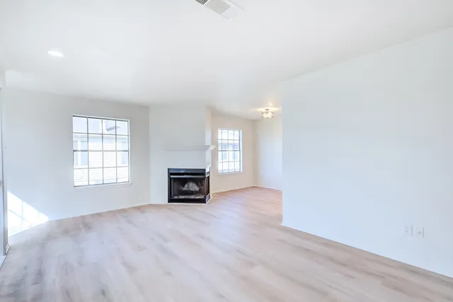 an empty room with windows and fireplace