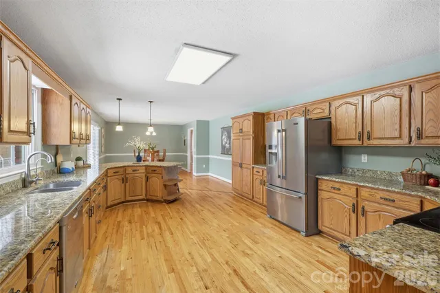 a kitchen with stainless steel appliances granite countertop a sink dishwasher stove and refrigerator with wooden floor