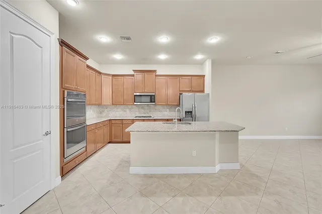 a large kitchen with kitchen island a sink stainless steel appliances and cabinets