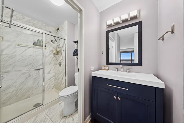 a bathroom with a double vanity sink toilet mirror and shower