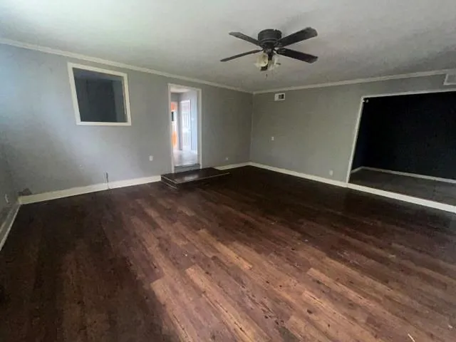 a view of an empty room with window and a ceiling fan