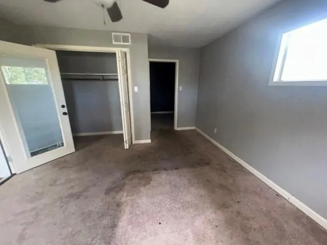 an empty room with a ceiling fan and windows
