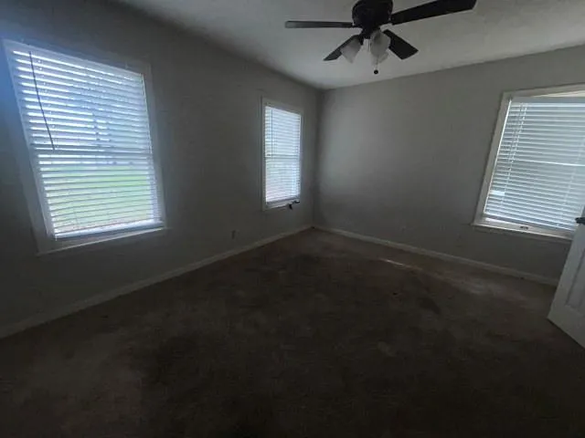 an empty room with windows and fan