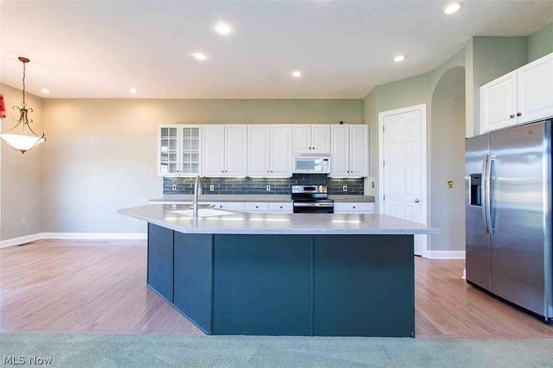 2201 Granger Road Medina, OH 44256 - Photo 11 of 34 Two tone kitchen with stainless steel appliances, a center island with sink, hanging light fixtures, light wood finished floors, and two tone cabinets