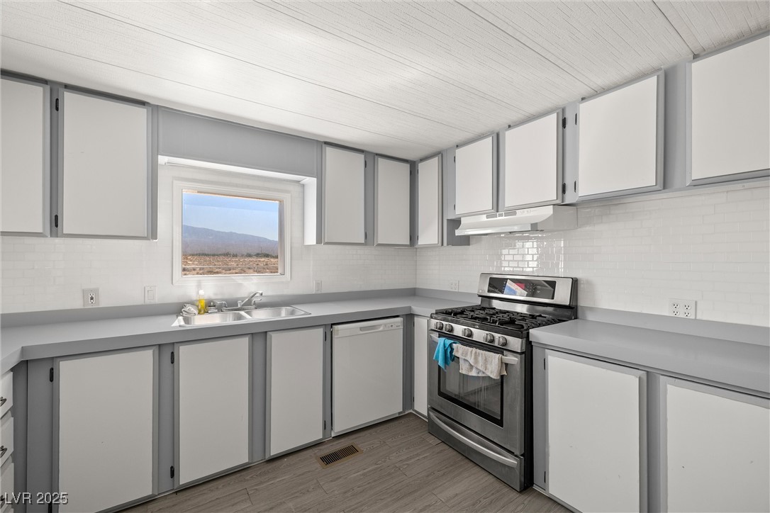 2150 West Harris Farm Road Pahrump, NV 89060 - Photo 17 of 33 Kitchen featuring stainless steel gas stove, dishwasher, under cabinet range hood, decorative backsplash, and light countertops