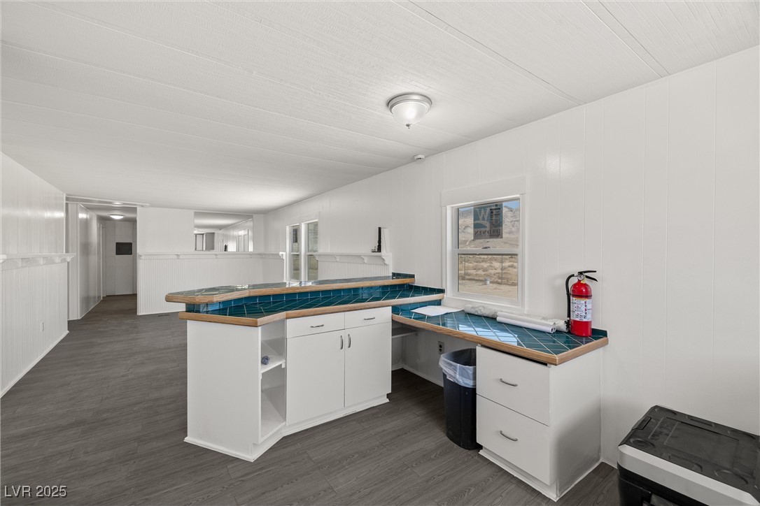 2150 West Harris Farm Road Pahrump, NV 89060 - Photo 18 of 33 Kitchen with white cabinets, open shelves, tile countertops, dark wood finished floors, and a decorative wall