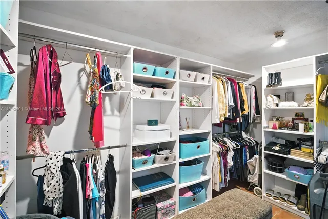 a view of walk in closet with clothes and shoes