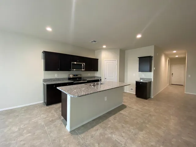 a large kitchen with a large counter top stainless steel appliances and cabinets