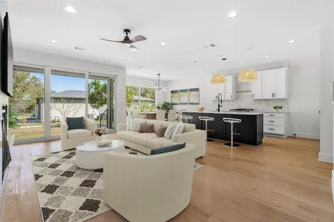 a living room with stainless steel appliances kitchen island granite countertop a sink and a counter top space