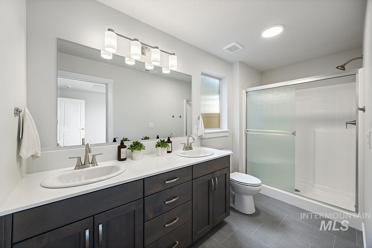 283 West Norwich Street Meridian, ID 83642 - Photo 13 of 25 Bathroom with double vanity, a stall shower, and dark tile patterned floors