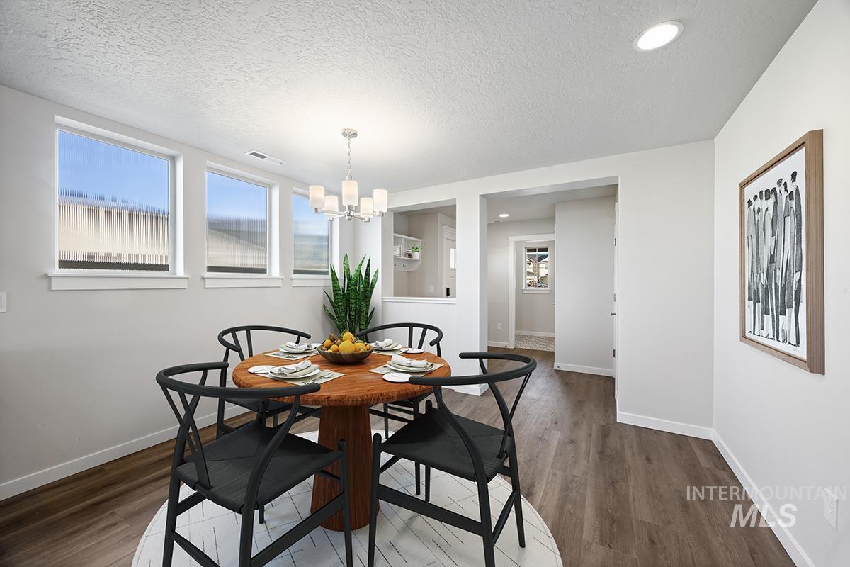 283 West Norwich Street Meridian, ID 83642 - Photo 4 of 25 Dining area with a textured ceiling, healthy amount of natural light, a chandelier, dark wood-style floors, and recessed lighting