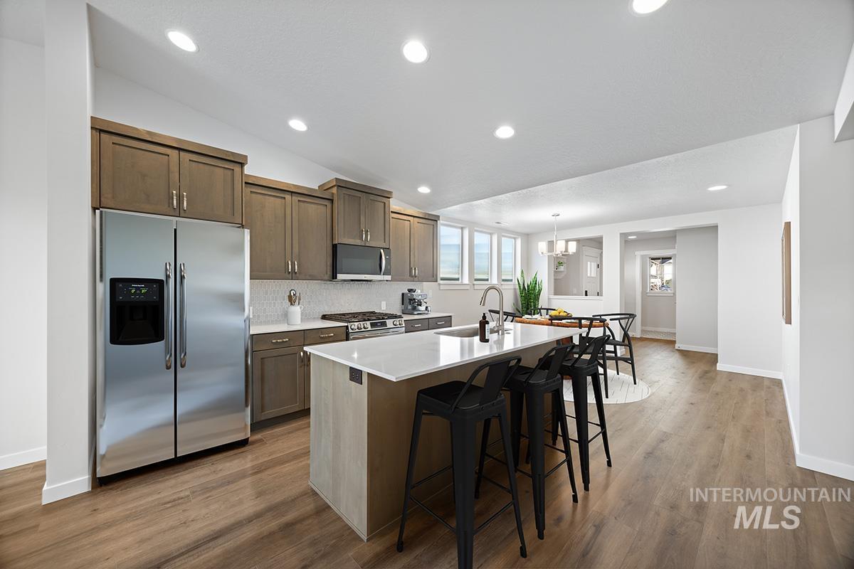 283 West Norwich Street Meridian, ID 83642 - Photo 6 of 25 Kitchen featuring appliances with stainless steel finishes, a kitchen bar, an island with sink, lofted ceiling, and decorative light fixtures