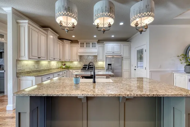 a kitchen with kitchen island granite countertop stainless steel appliances a sink stove and refrigerator