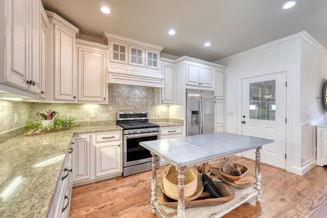 a kitchen with stainless steel appliances granite countertop a stove top oven a sink dishwasher and refrigerator with wooden floor