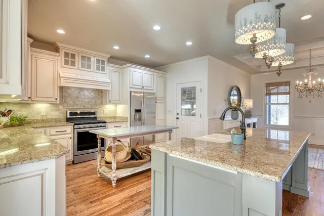 a kitchen with stainless steel appliances granite countertop a sink dishwasher a stove and a dining table with wooden floor