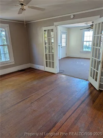a view of an empty room with a window and wooden floor