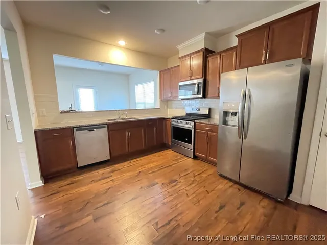 a kitchen with granite countertop stainless steel appliances a refrigerator a sink a stove top oven and cabinets