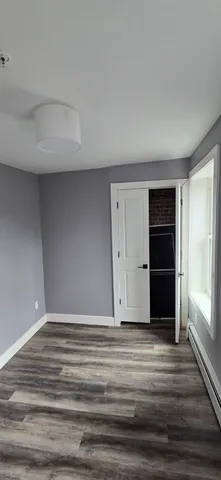 a view of an empty room with wooden floor and closet