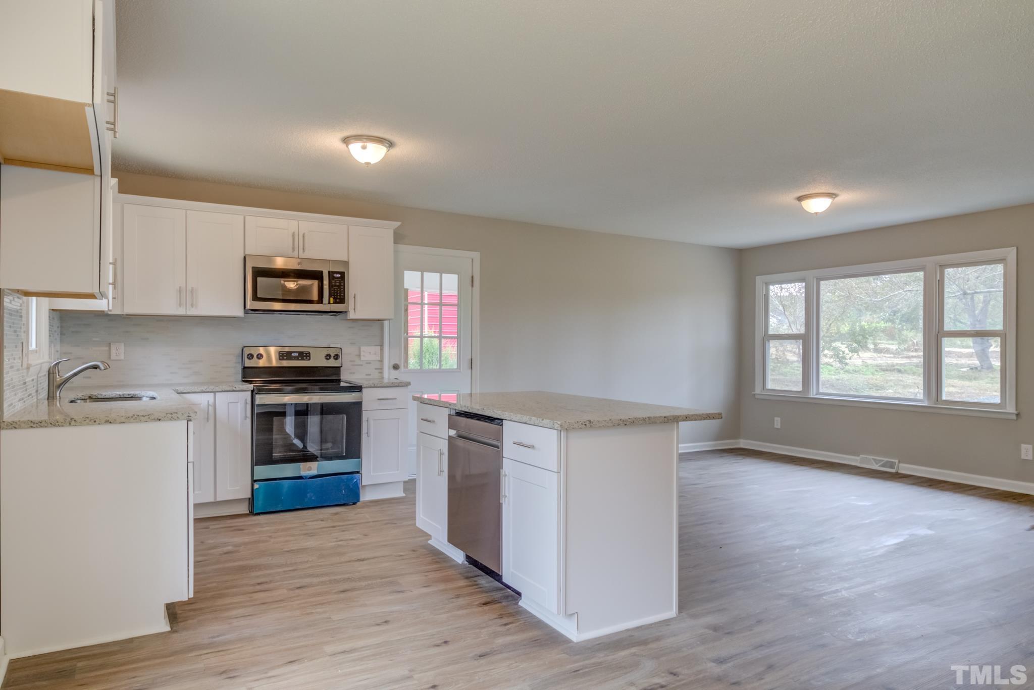 3600 Edgemont Road Wendell, NC 27591 - Photo 11 of 30 a kitchen with stainless steel appliances a stove a sink a refrigerator white cabinets and wooden floor