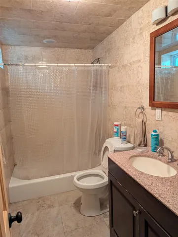 a bathroom with a granite countertop bathtub sink vanity mirror and toilet
