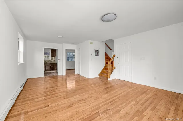 a view of empty room with wooden floor and kitchen