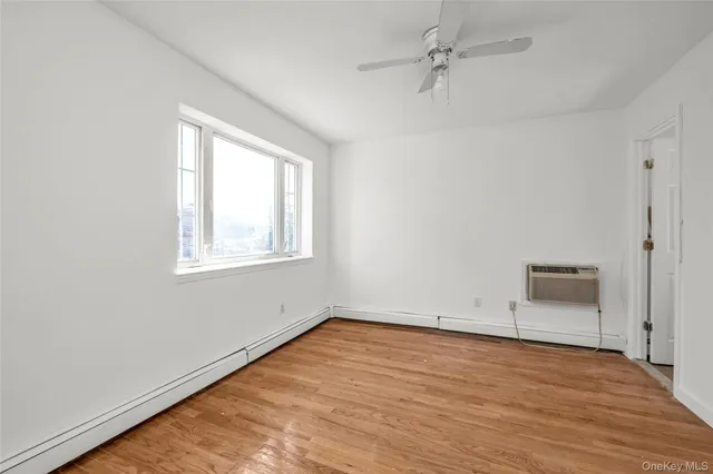 an empty room with a window and a ceiling fan