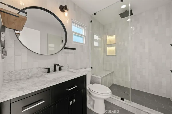 a bathroom with a granite countertop sink toilet a mirror and shower