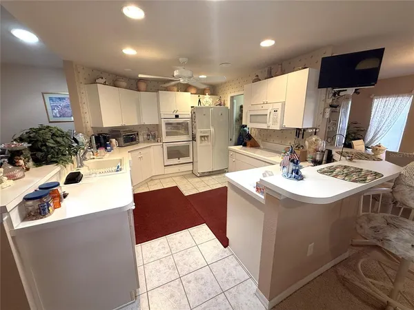 a kitchen with stainless steel appliances kitchen island granite countertop a sink and white cabinets