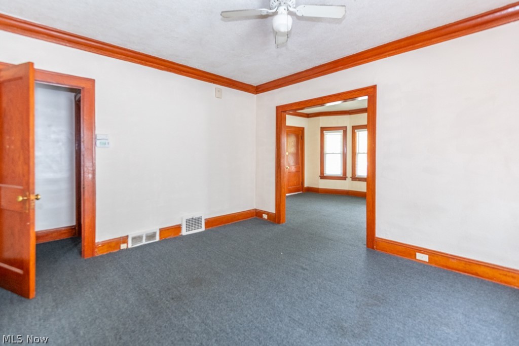 917 Helmsdale Road Cleveland Heights, OH 44112 - Photo 8 of 28 Unfurnished room featuring carpet floors, ornamental molding, ceiling fan, and a textured ceiling