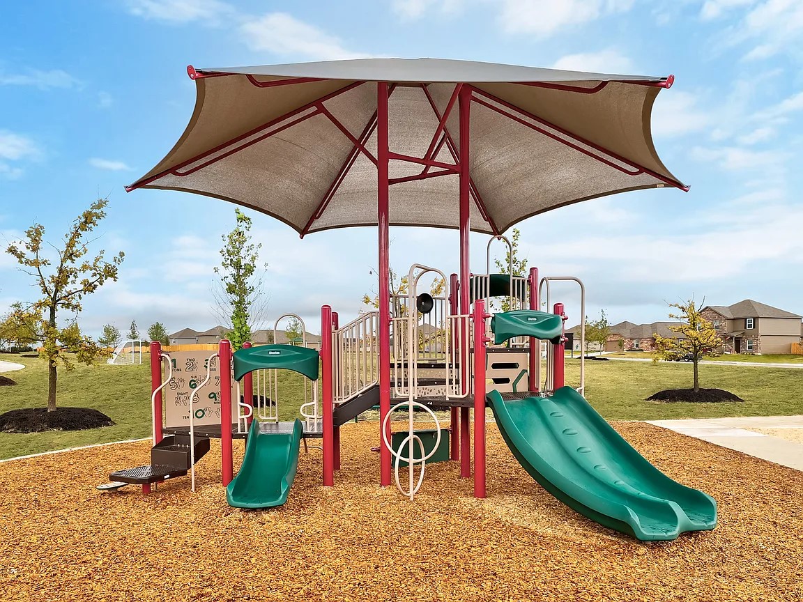 14024 Prairie Schooner Pass Elgin, TX 78621 - Photo 19 of 20 Playground structure featuring a fabric sunshade, multiple slides, and climbing elements over a wood chip surface