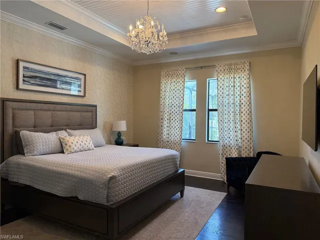 a bedroom with a large bed and a chandelier