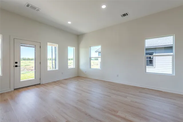 an empty room with wooden floor and windows