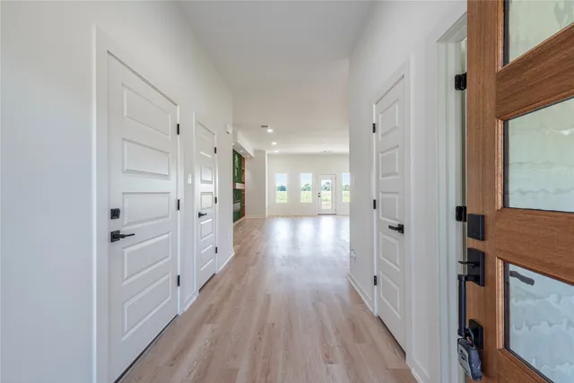 a view of a hallway with wooden floor and a bathroom
