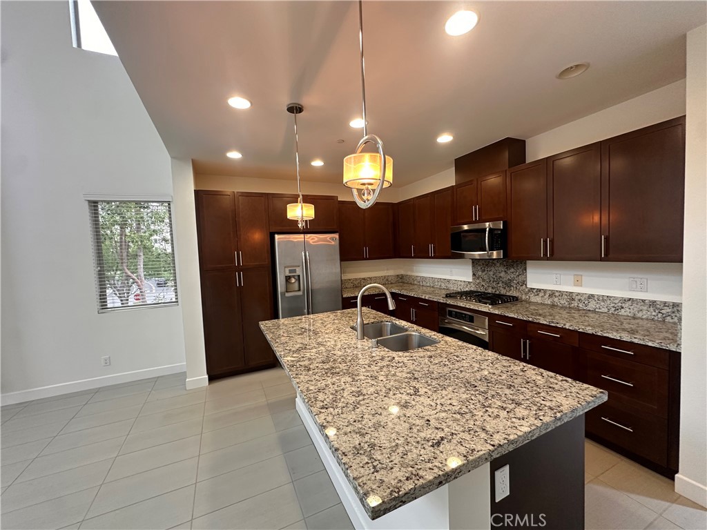 27 Soho Irvine, CA 92612 - Photo 13 of 69 a kitchen with stainless steel appliances granite countertop a sink a stove and a wooden cabinets
