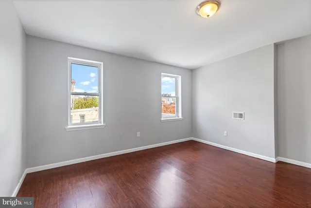 an empty room with wooden floor and windows