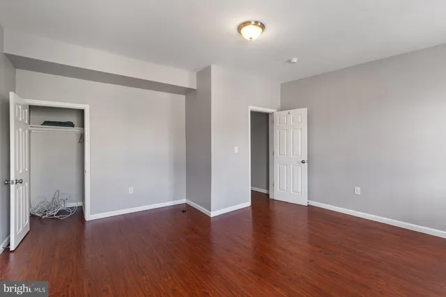 an empty room with wooden floor and a bathroom