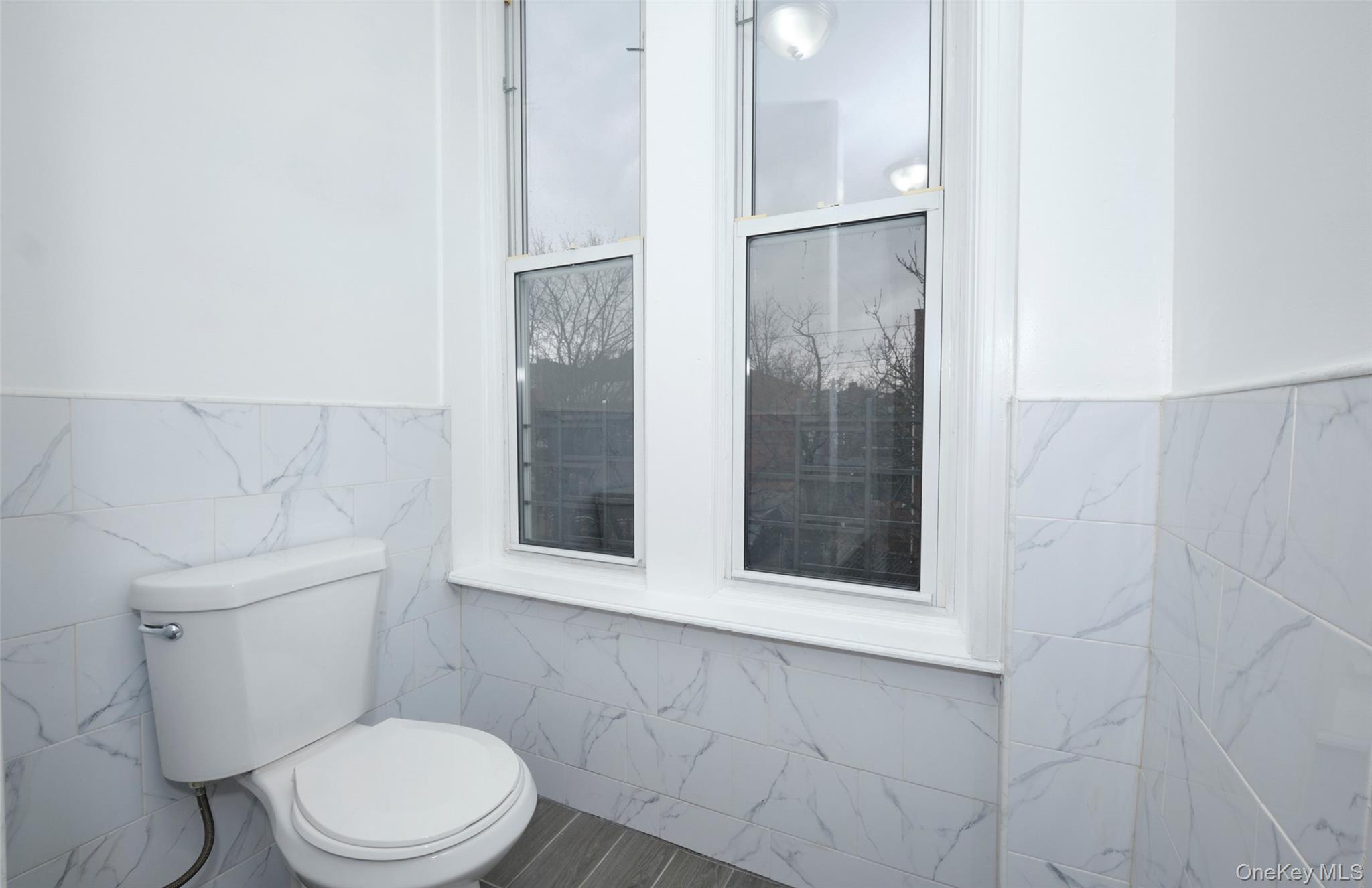 563 Miller Avenue Brooklyn, NY 11207 - Photo 13 of 21 Half bathroom with tile walls and a wainscoted wall