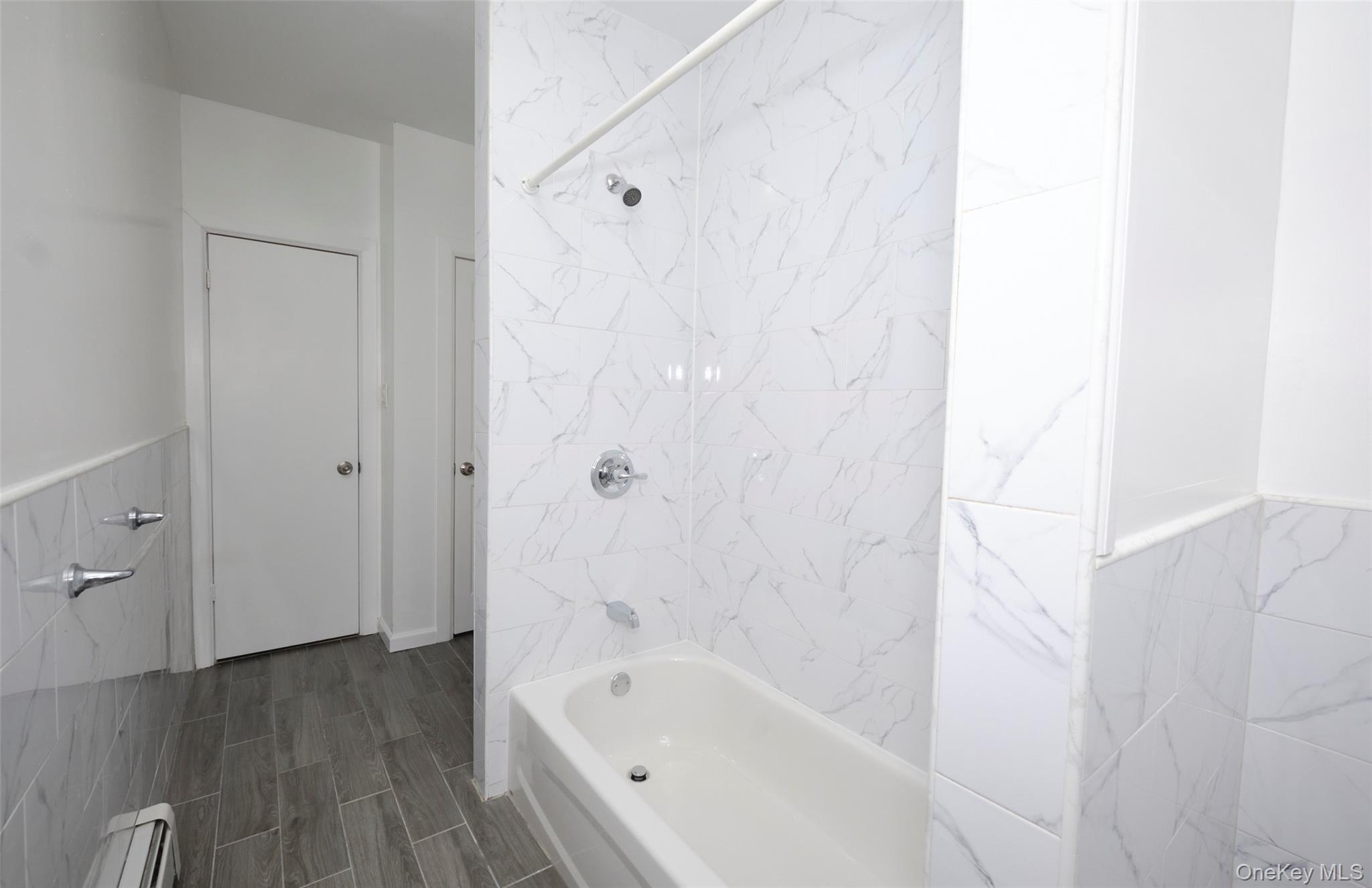563 Miller Avenue Brooklyn, NY 11207 - Photo 14 of 21 Bathroom with shower combination, a baseboard heating unit, and a wainscoted wall