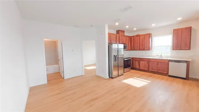 a kitchen with stainless steel appliances kitchen island granite countertop a refrigerator and a sink