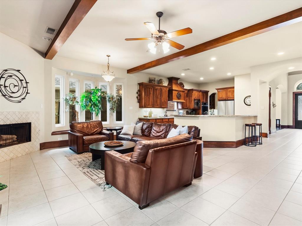 1615 Roma Lane Allen, TX 75013 - Photo 12 of 36 Spacious interior with neutral tile flooring, a fireplace featuring a diamond-patterned tile surround, and a kitchen with warm wood cabinetry