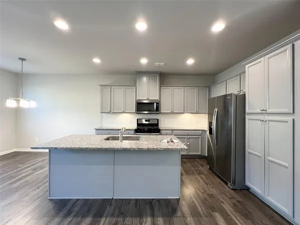 a kitchen with kitchen island granite countertop wooden cabinets and refrigerator