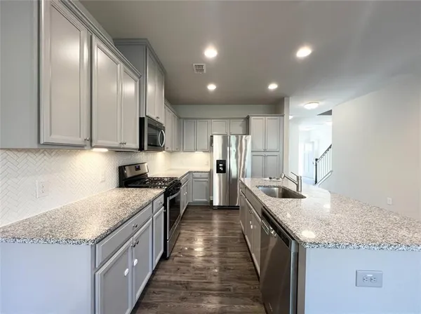 a kitchen with granite countertop kitchen island stainless steel appliances sink stove microwave and cabinets