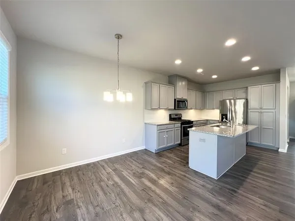 a kitchen with stainless steel appliances granite countertop a sink a stove and a wooden floors