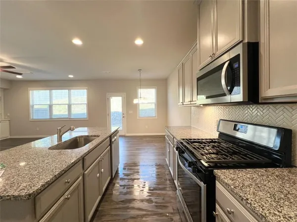 a kitchen with granite countertop stainless steel appliances a sink stove top oven and microwave