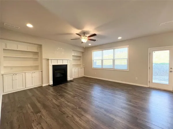 an empty room with windows a fireplace and wooden floor