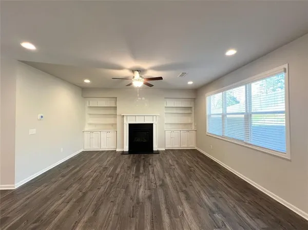 a view of an empty room with a window and wooden floor