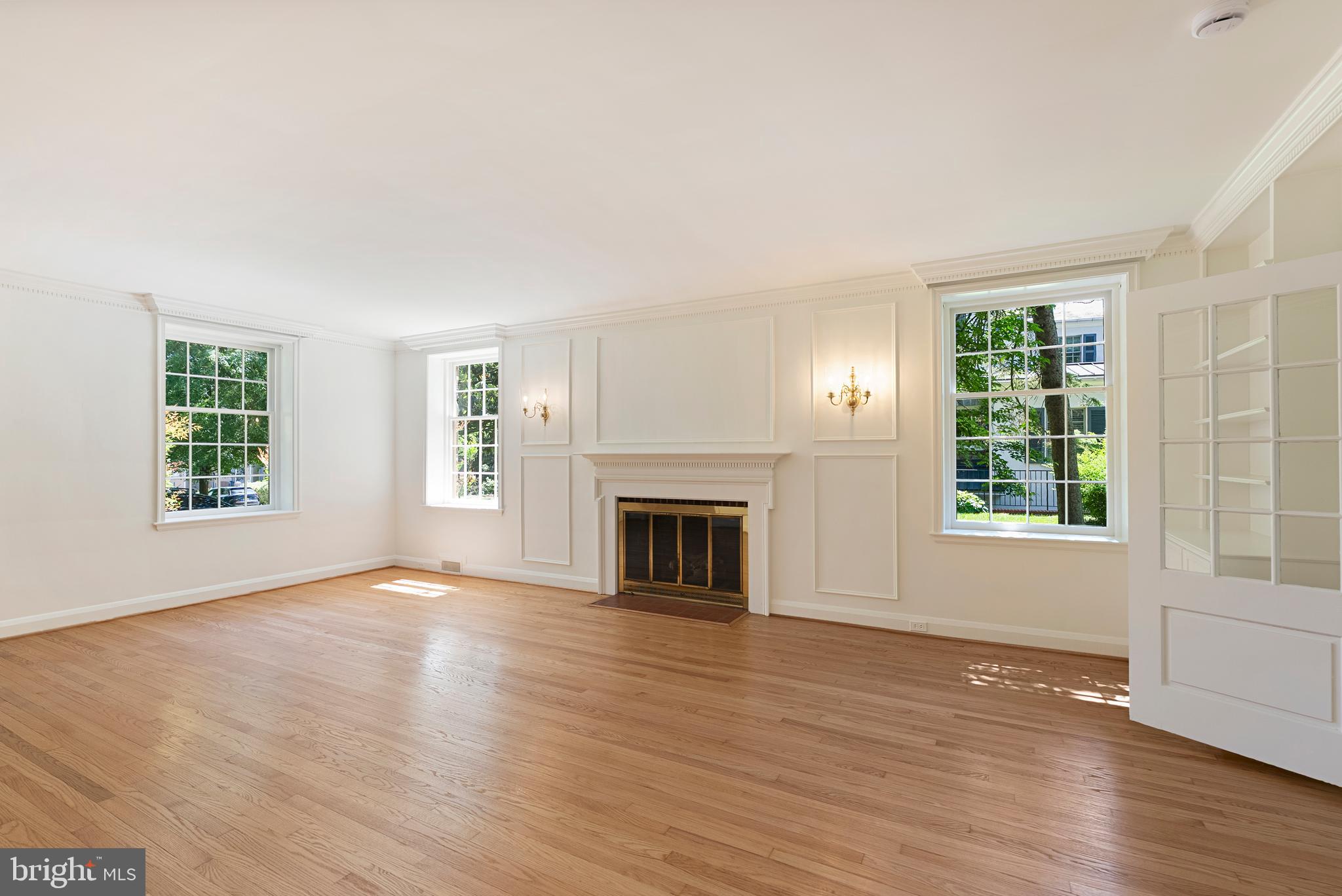 602 Stoneleigh Road Baltimore, MD 21212 - Photo 6 of 31 an empty room with windows a fireplace and wooden floor