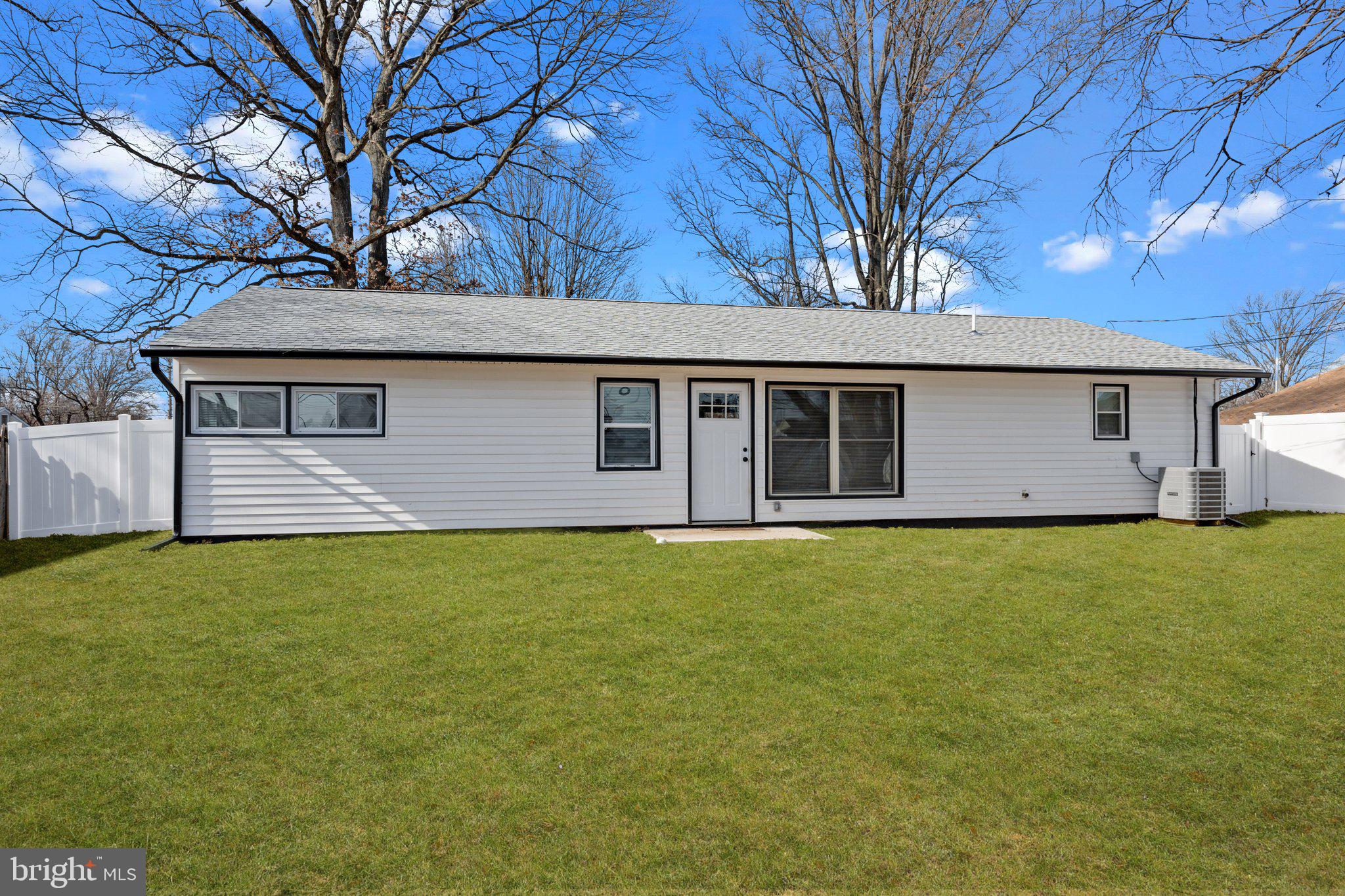 26 Oaktree Drive Levittown, PA 19055 - Photo 19 of 19 a backyard of a house with large trees and brick wall