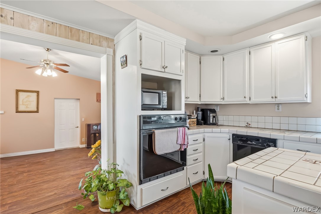 2401 North Stephan Road Kingman, AZ 86401 - Photo 29 of 92 Kitchen featuring white cabinetry, tile countertops, a built-in oven, a microwave, and wood-finish flooring