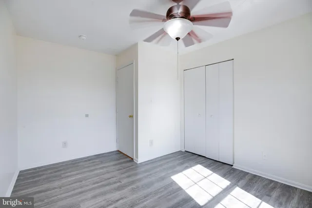 an empty room with wooden floor chandelier fan and closet